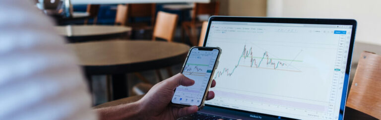 Investment-Ausblick Q3 2025 1 Person vor Laptop mit Investmentcharts – analysiert aktuelle Markttrends am Smartphone.