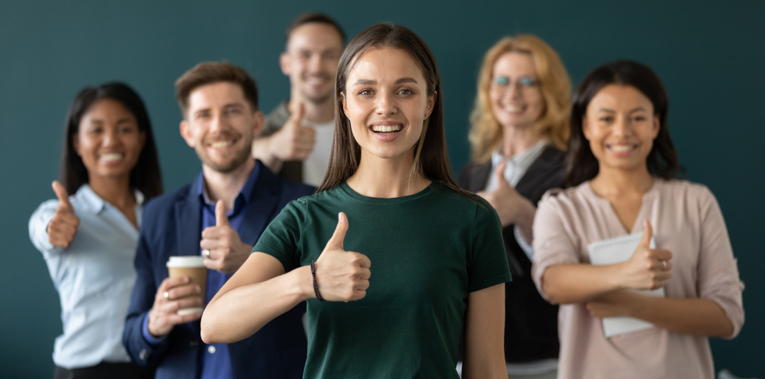 Mehrere junge Menschen zeigen lachend den Daumen nach oben als Symbol für Weiterempfehlung