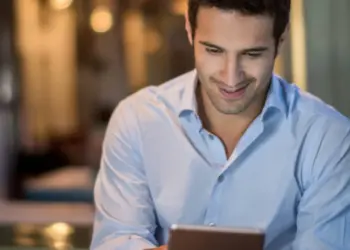 Junger Mann liest digitale Kundennews auf einem Tablet