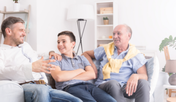 Versicherungen nach Lebensphase - Glückliche Generationen – Sohn, Vater und Großvater sitzen gemeinsam auf der Couch