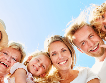 Drei Generationen einer Familie lachen gemeinsam in die Kamera – Symbol für sichere Altersvorsorge